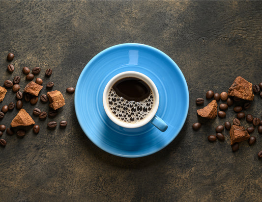 Cup of chaga coffee on blue plate with chaga and coffee beans on both sides.