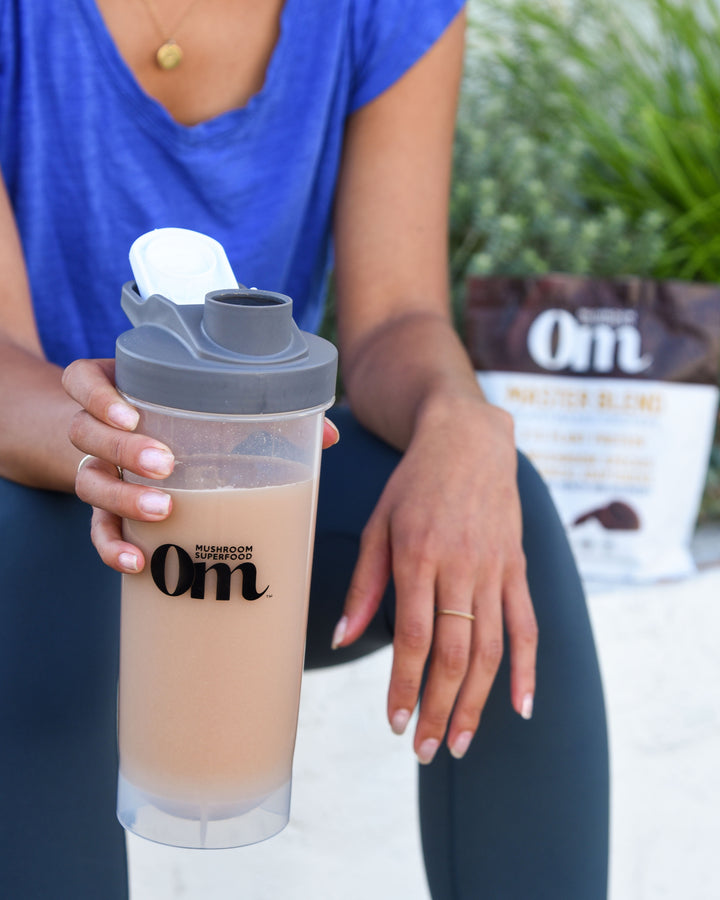 A woman enjoying a mushroom pre-workout drink made with an Om Mushroom supplement.