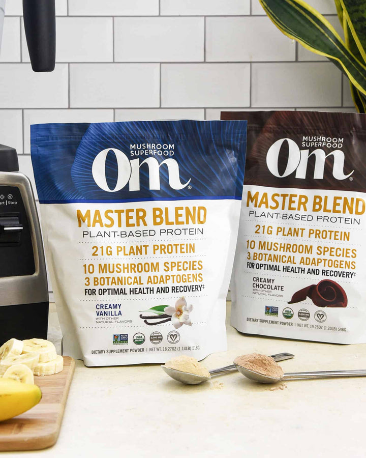 Two bags and scoops of Om’s Master Blend Plant-Based Protein powder.
