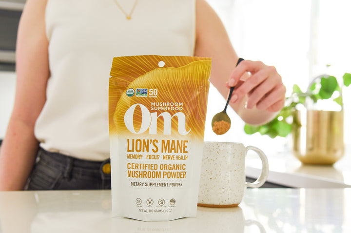Woman stirring cup of Om coffee for natural supplements for gut health.