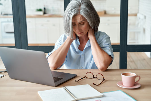 Fatigued woman on laptop rubbing her neck with closed eyes