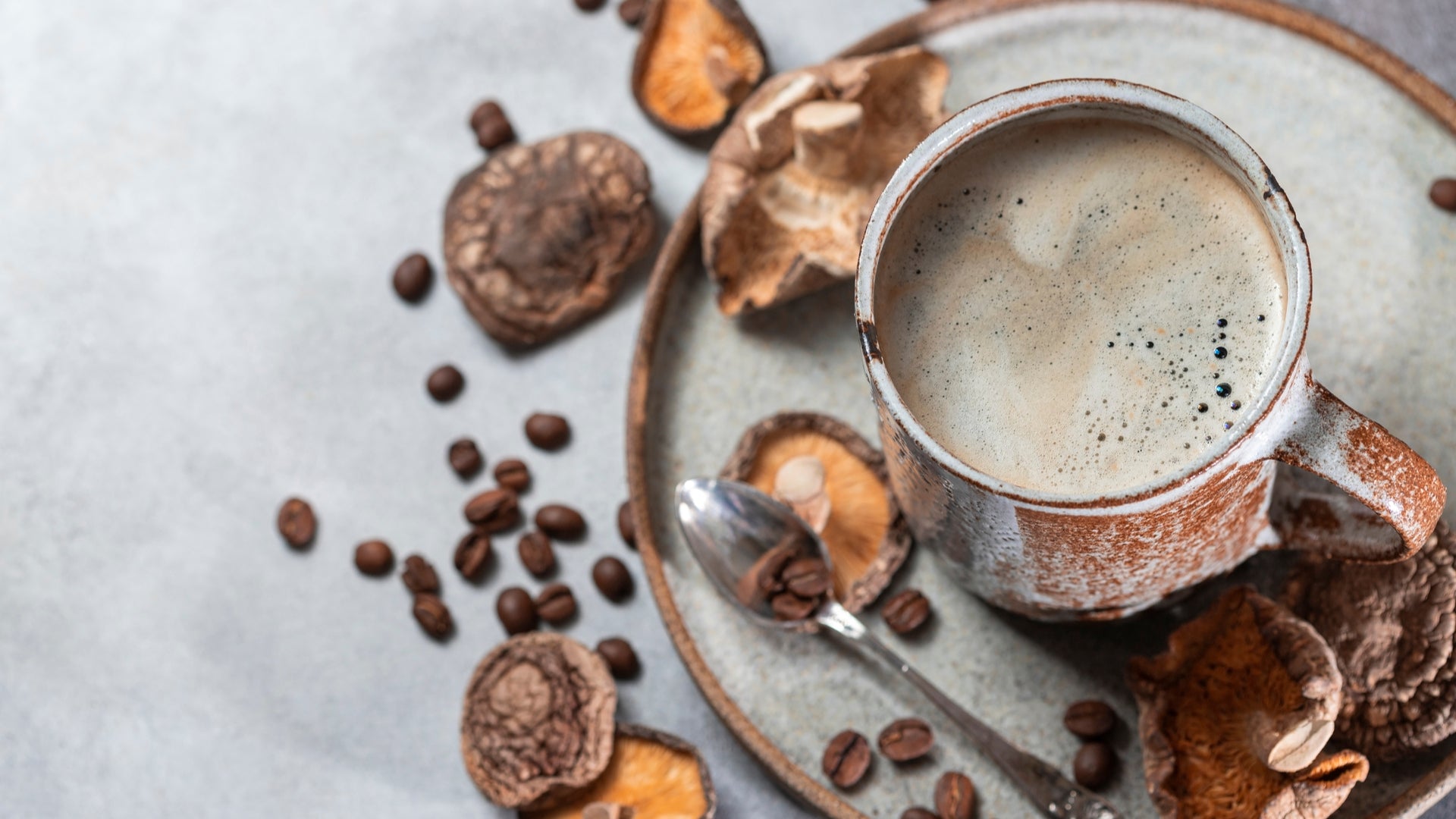 Cup of energy-providing beverage surrounded by mushrooms on plate.