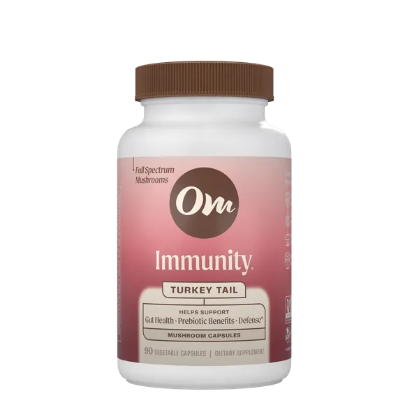 Om Immunity Turkey Tail capsules in front of a Turkey Tail mushroom