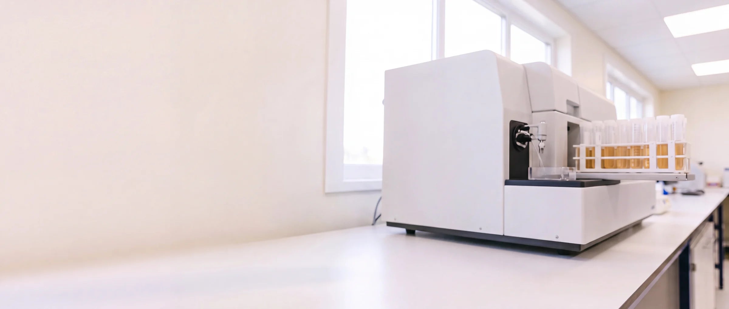 A clean lab bench with a metals-testing instrument open, more instruments further down the counter.